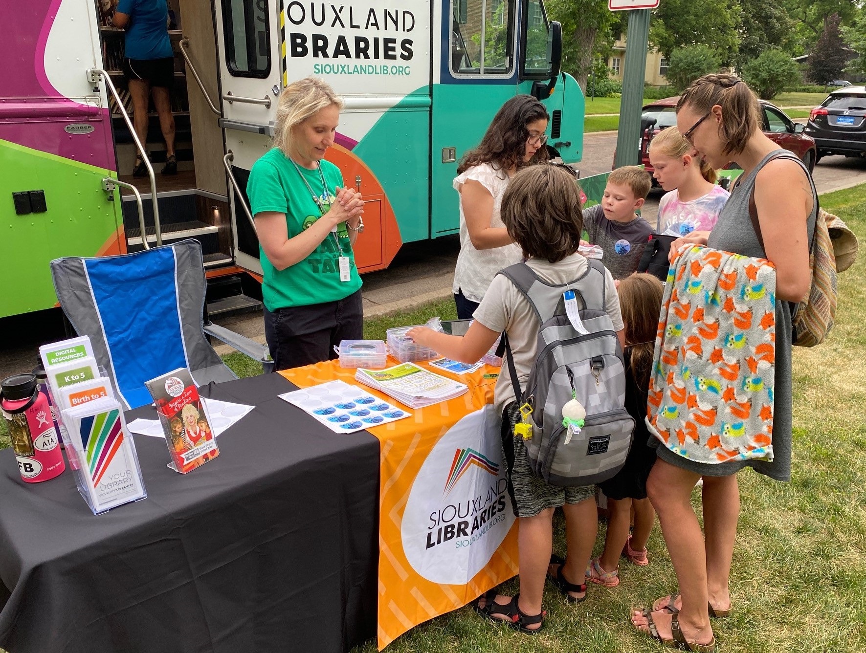 Library staff assist customers at a table set up just outside the Bookmobile.
