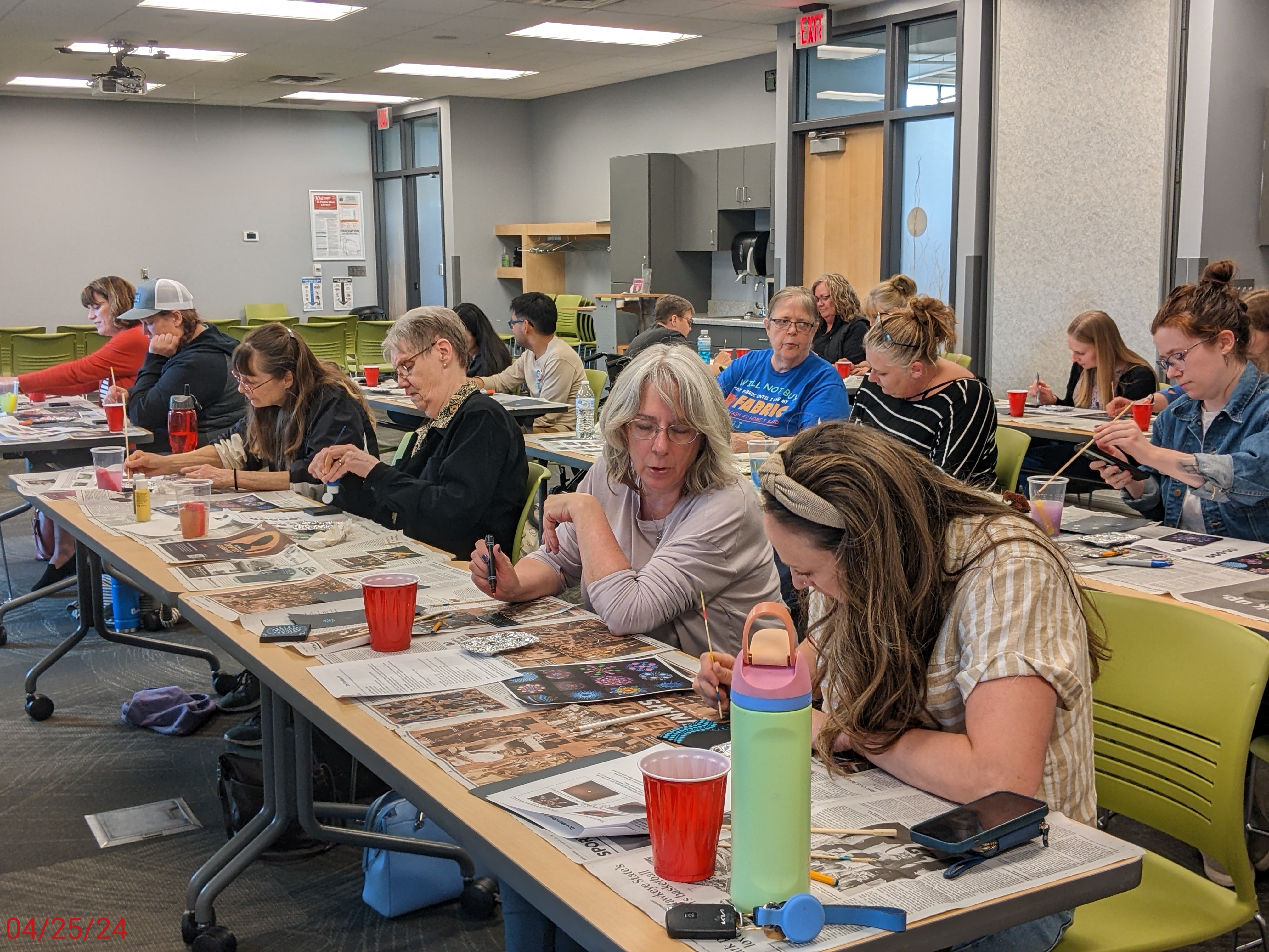 Library program attendees sit at tables, working on art projects.