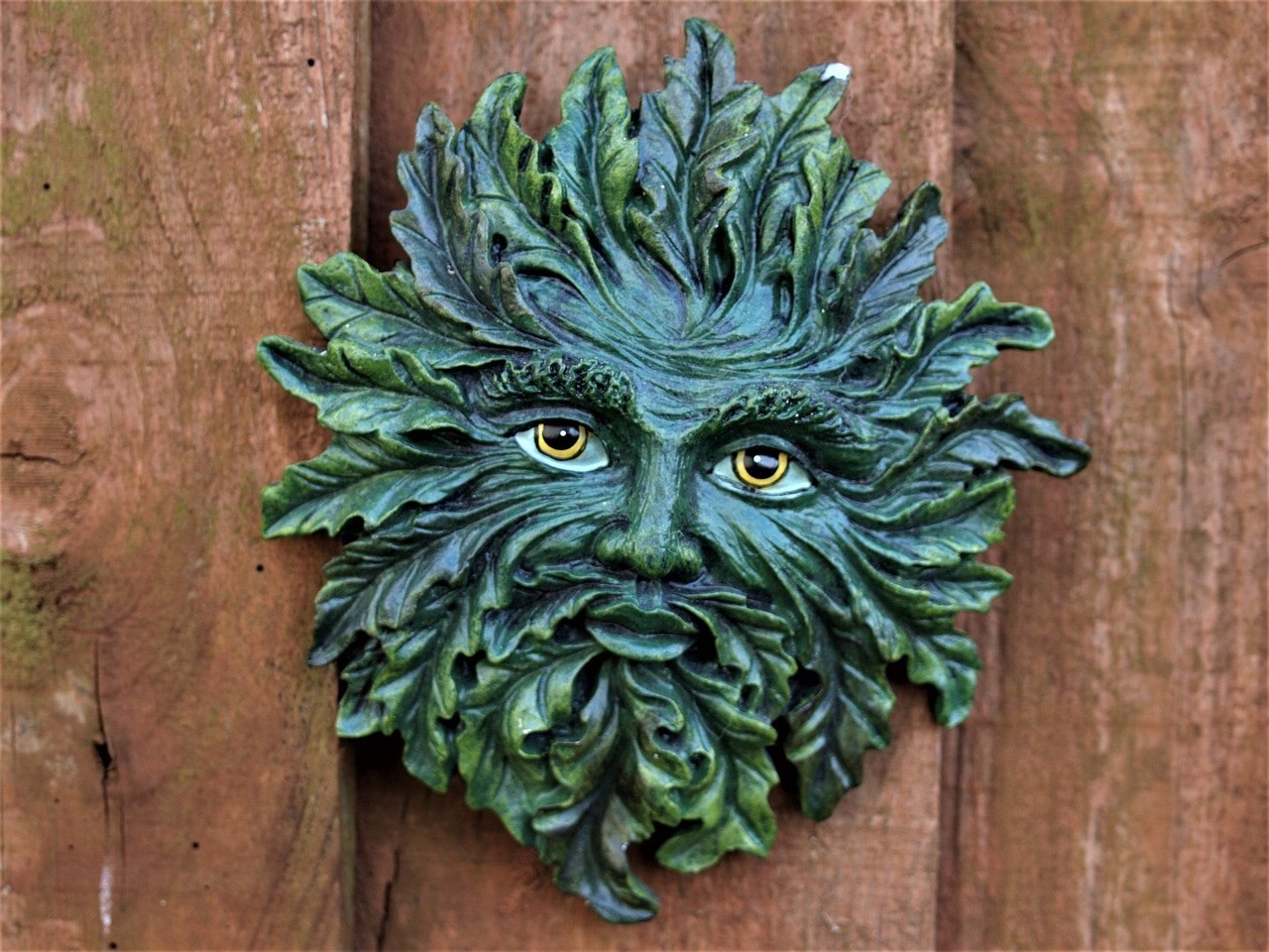 Decorative head of a green man's face, surrounded by foliage.