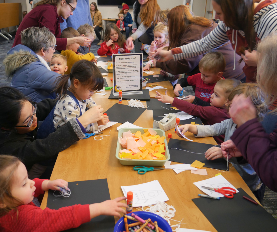 Children age birth to five years old working on a spaceship craft at a space themed sensory program.