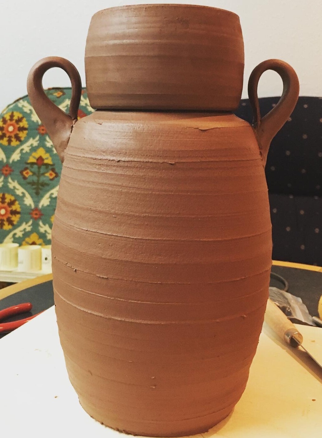 Unfired earthenware funerary urn with lid and handles.