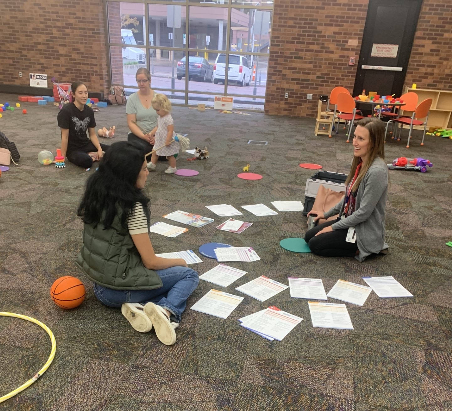 An expert at the Parent and Child Workshop sits on the floor with attendees.