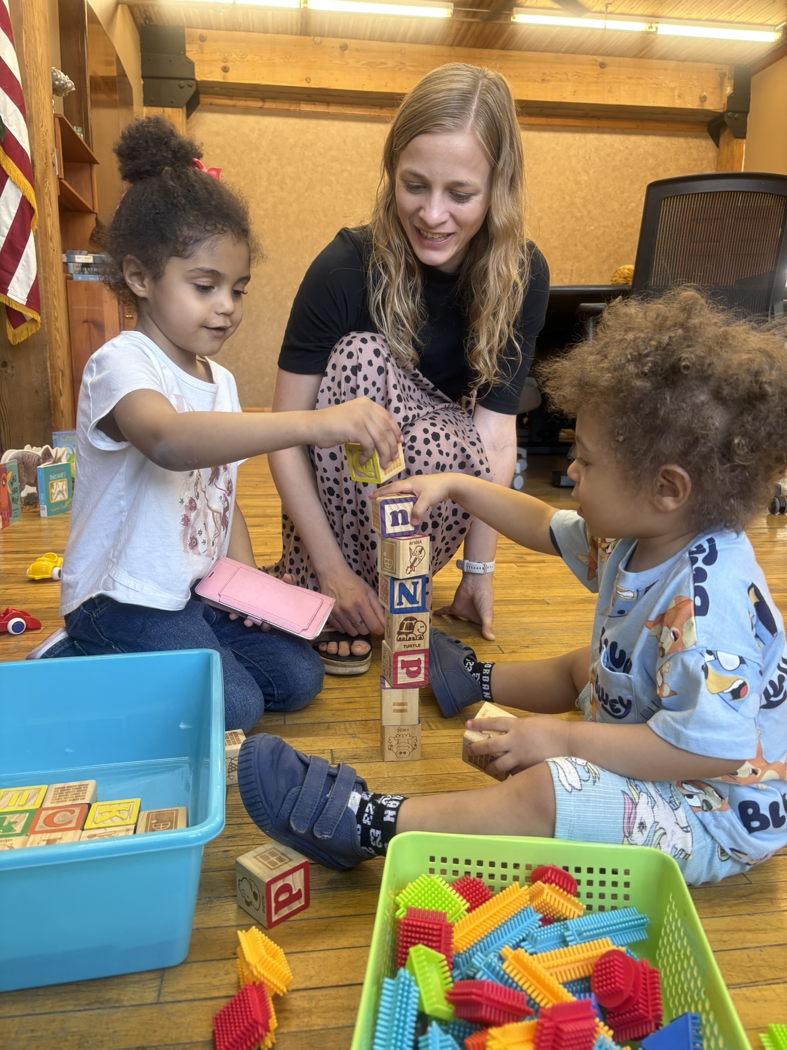 A library associate watches two small children play with blocks.