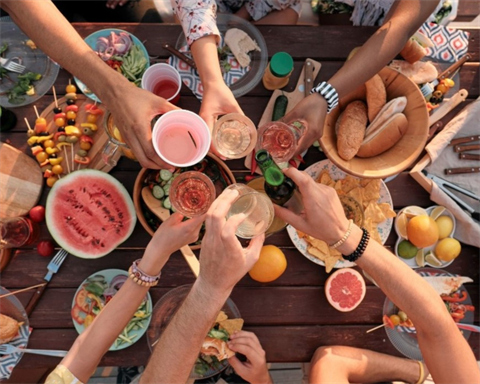 Guests put their drinks together over a table full of food.