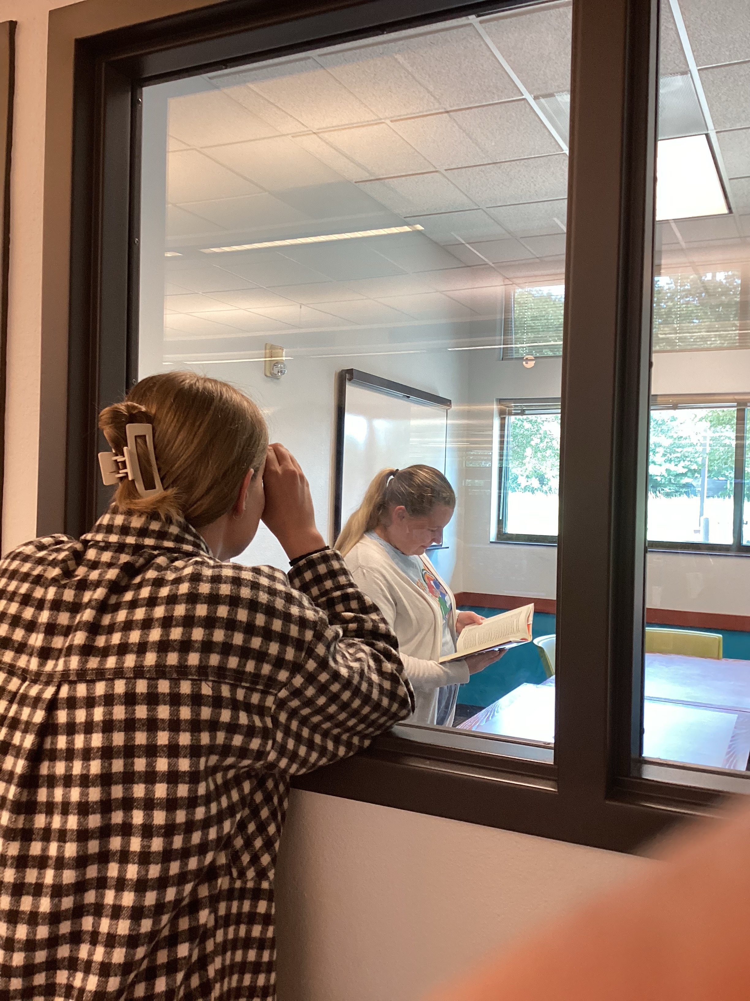 A staff member spies on Priscilla reading in the study room.