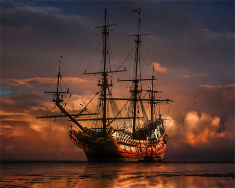 a pirate ship glowing in an orange sunset