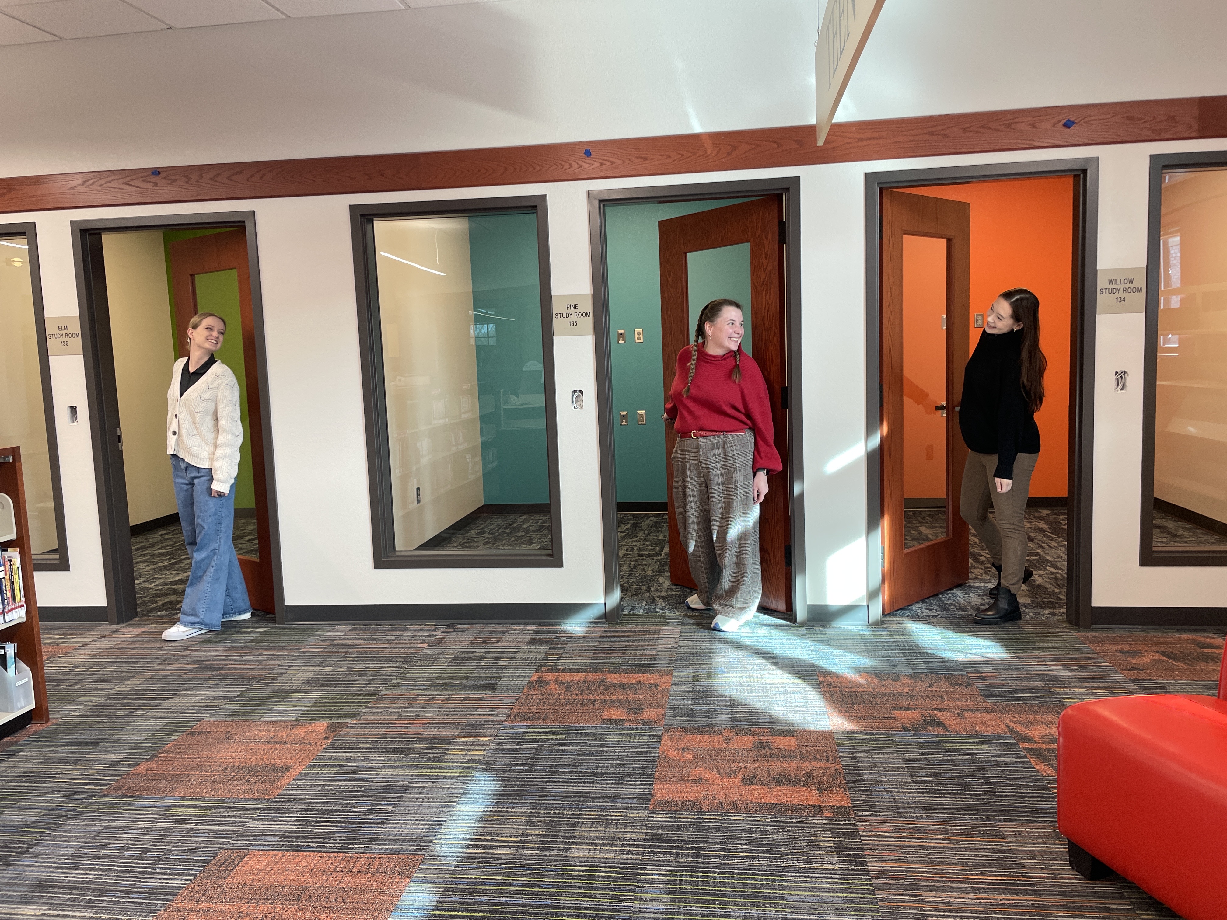 Library staff smile at each other inside new study rooms.