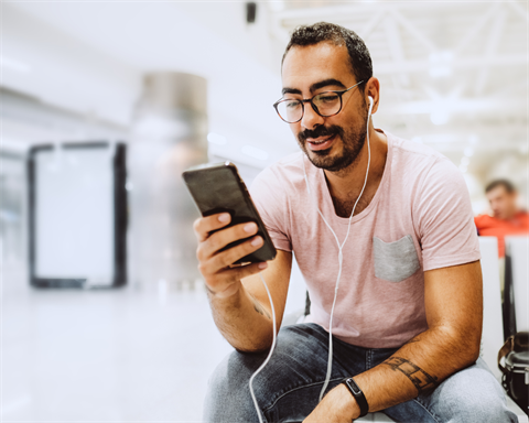 A man with earbuds in looks at his phone.