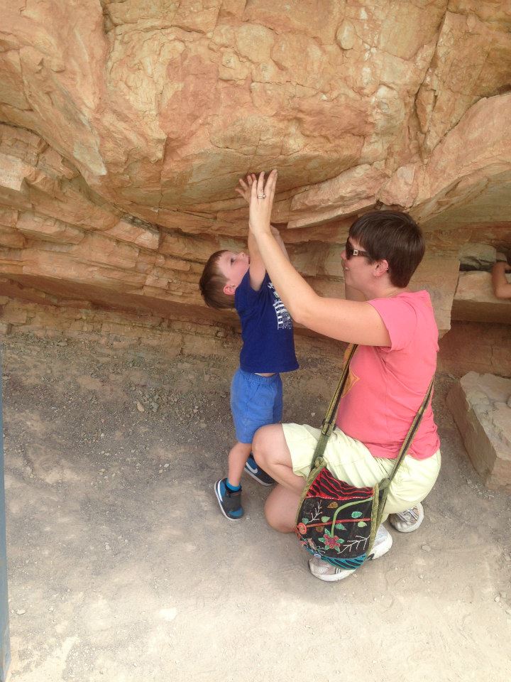 A mother and child touch the fossilized foot mold of an Apatosaurus.