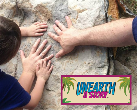 Hands are placed on a dinosaur footprint fossil.