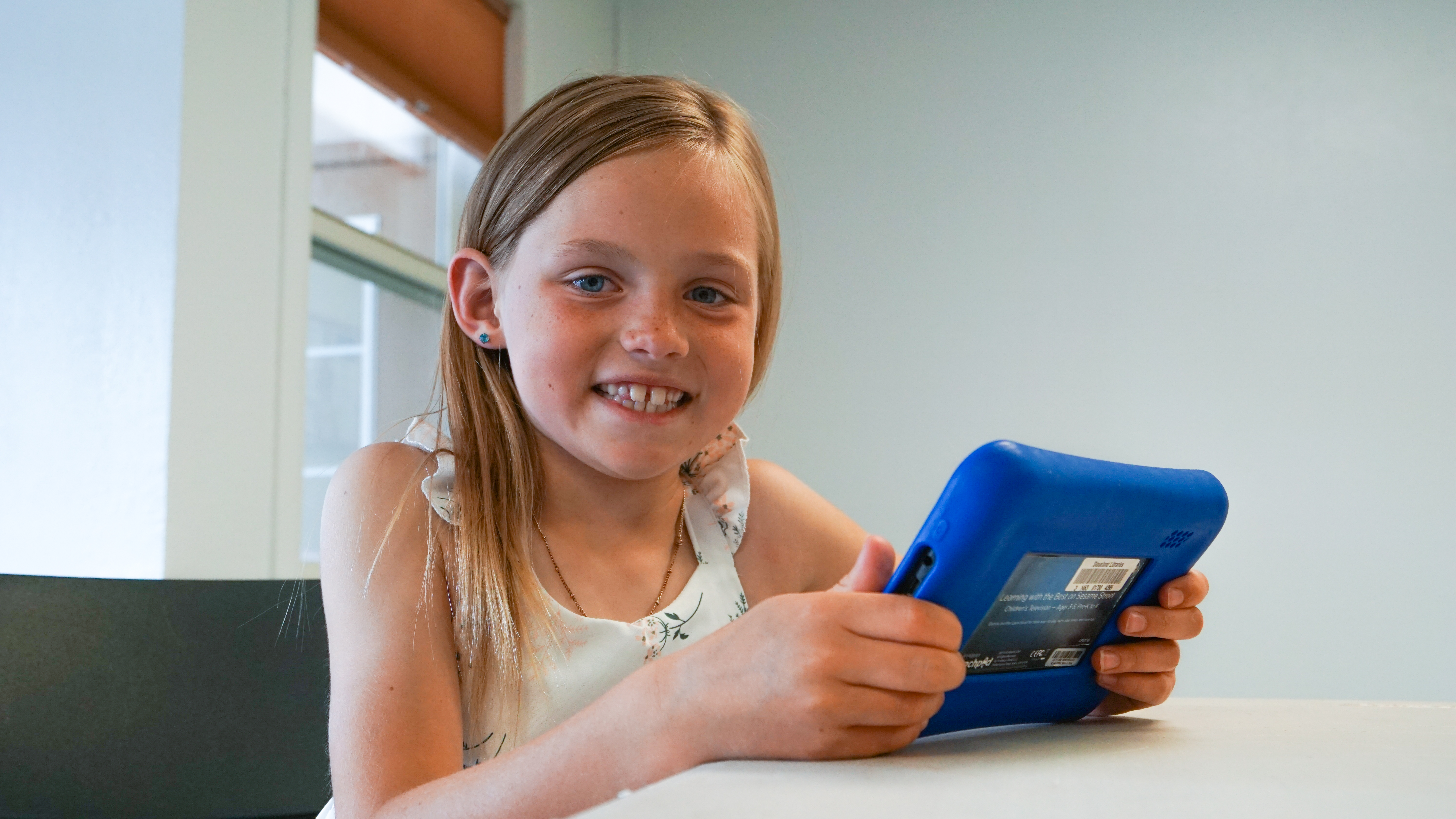 A smiling girl holds a library tablet.