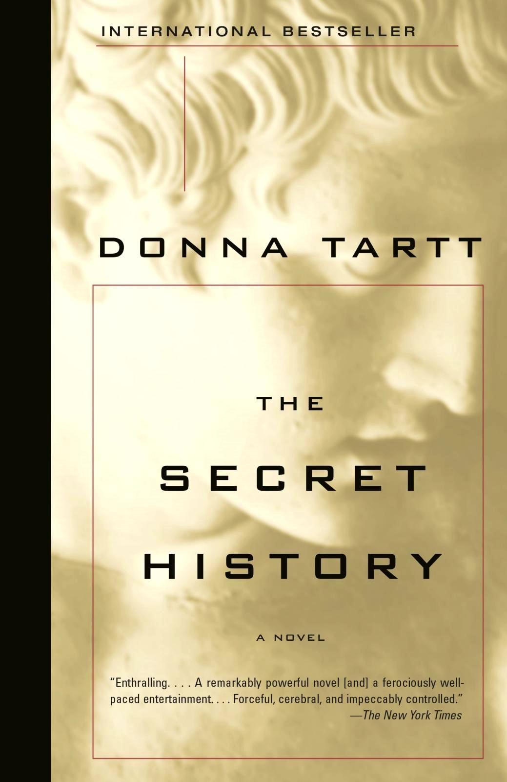 The image is the book cover for The Secret History by Donna Tartt. The background features a full-bleed, extreme close-up photo of a classical marble statue's face in warm, sepia-tinted golden tones. The left spine edge has a vertical solid black strip. A thin reddish-brown line forms a large rectangular box framing the central typography over the statue image.