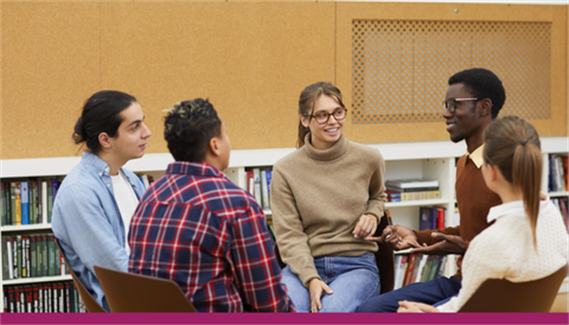 group of teens sitting in a circle having a discussion; bookshelves are in the background