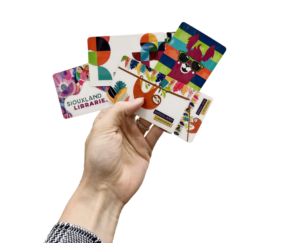 Hand holding 4 different library card designs. Designs feature a sloth, a llama, multicolored circles, and a collage cartoon animal figures.