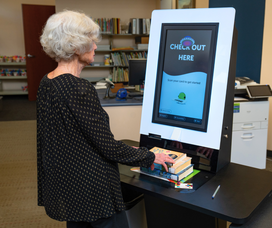 Customer using kiosk to self-checkout library items.