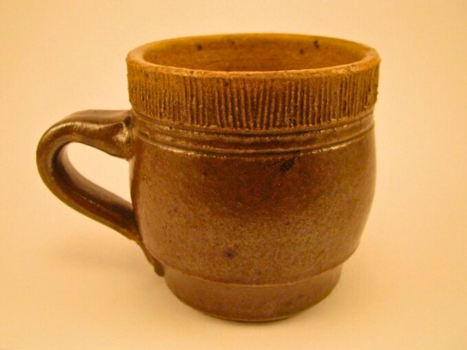 Cone 10 reduction stoneware brown cup with handle and textured rim.